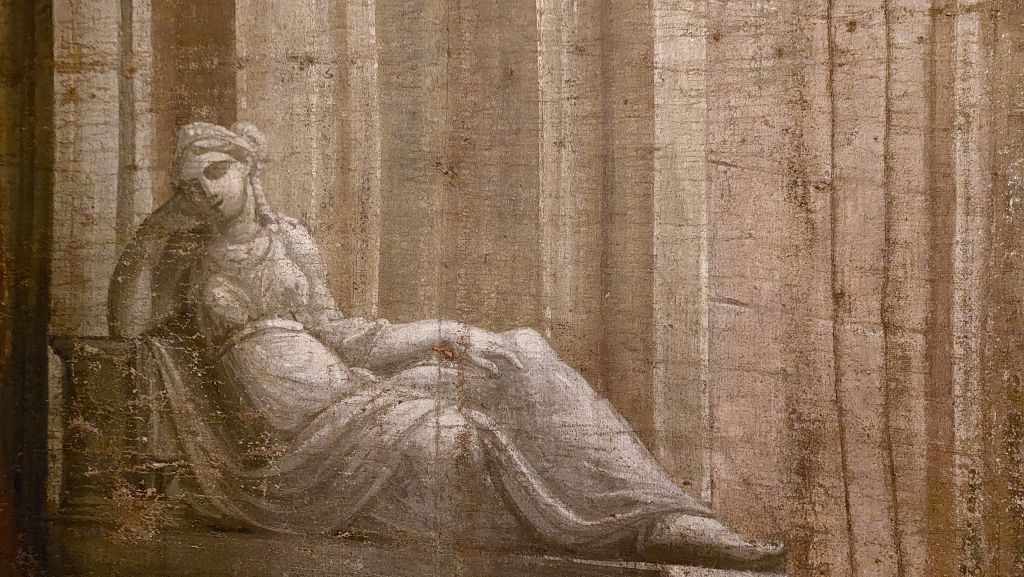 Una figura femminile che reclina su una panchina con le mani sul viso, vestita in abiti drappeggiati, in un ambiente con colonne sullo sfondo.